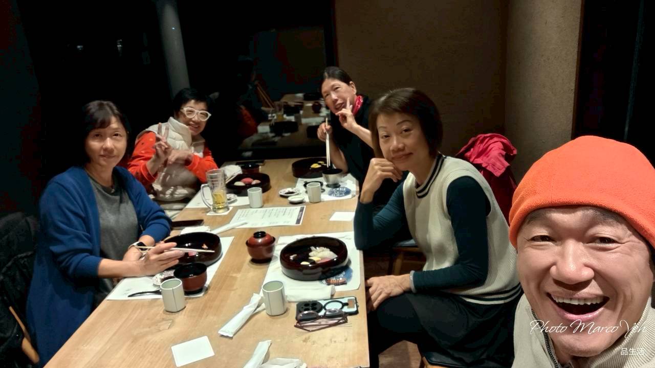 旅伴圍坐在餐桌旁,面向鏡頭微笑合影